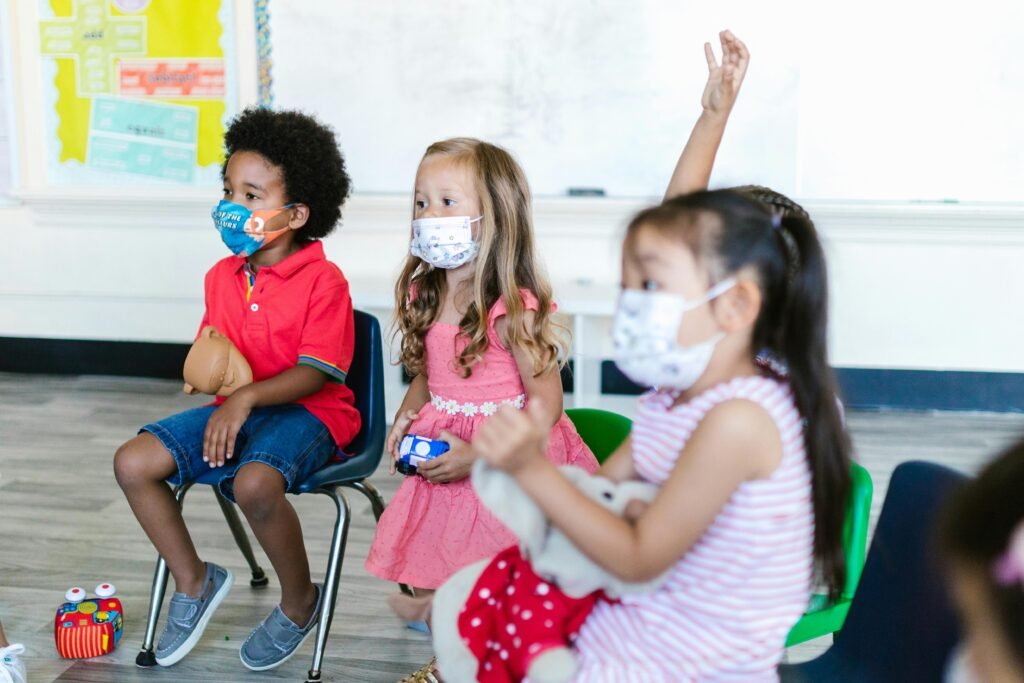 Children wearing face masks attentively participate in a preschool classroom.